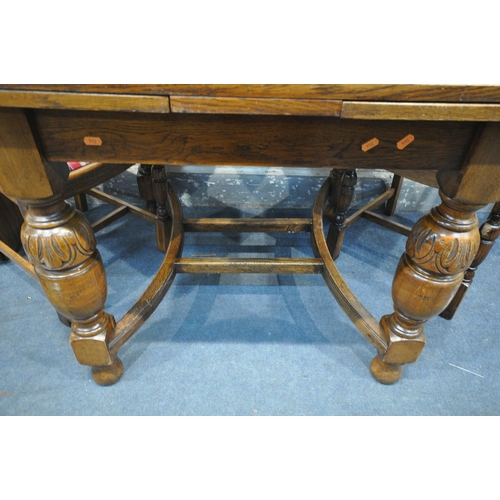 1206 - A 20TH CENTURY OAK EXTENDING DINING TABLE, on acorn legs, united by shaped stretchers, open length 1... 