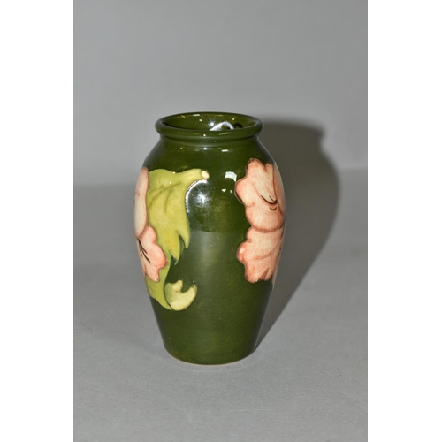 351 - A MOORCROFT POTTERY BALUSTER SHAPED BUD VASE DECORATED WITH CORAL HIBISCUS ON A GREEN GROUND, impres... 