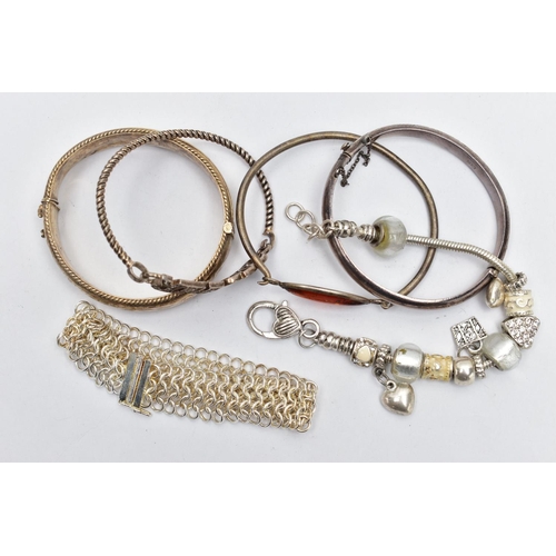 29 - TWO SILVER BANGLES AND ASSORTED WHITE METAL BRACELETS, the first a hinged bangle with floral engravi... 