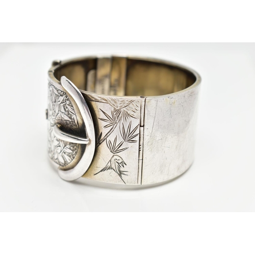 64 - A WHITE METAL HINGED BANGLE, wide bangle approximate width 30.3mm, in the form of a belt and buckle ... 