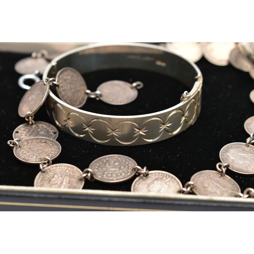 81 - TWO BANGLES AND A COIN NECKLACE, to include a silver hinged bangle with scroll engraved detail and r... 