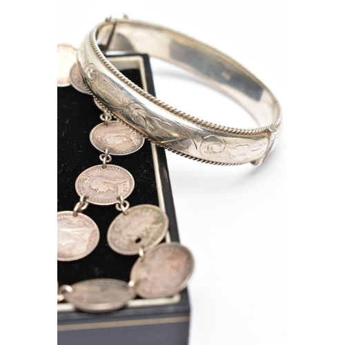 81 - TWO BANGLES AND A COIN NECKLACE, to include a silver hinged bangle with scroll engraved detail and r... 