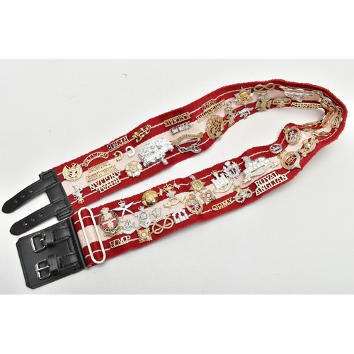 157 - A RED AND WHITE MILITARY STYLE STABLE BELT, which has had mounted over 45 Military Badges, Cap devic... 