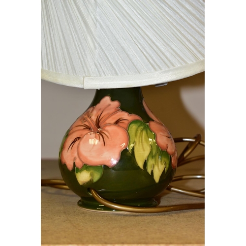 318 - A MOORCROFT TABLE LAMP, decorated in the  Coral Hibiscus pattern on a green ground with a cream shad... 