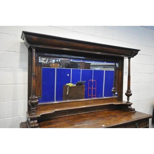 1235 - AN EARLY 20TH CENTURY OAK MIRRORBACK SIDEBOARD, with an overhanging top, supported on geometric beve... 