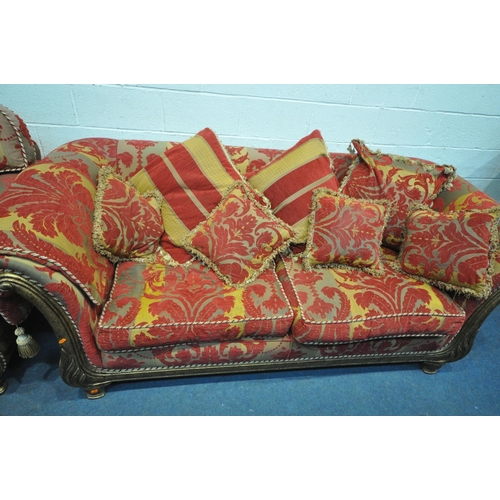 1308 - A RED FLORAL UPHOLSTERED THREE PIECE LOUNGE SUITE, comprising a three seater sofa, a wide armchair, ... 