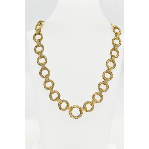 17 - A YELLOW METAL CHAIN NECKLACE, a wide chain comprised of hollow circular filagree links fitted toget... 