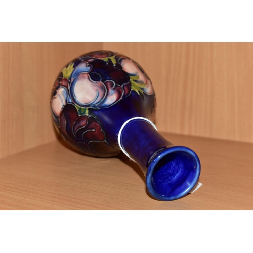 312 - A MOORCROFT POTTERY BUD VASE, tube lined pink and purple Anemone pattern on a blue ground, impressed... 