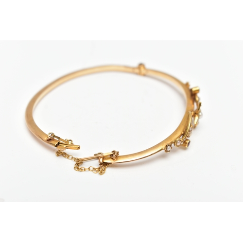 38 - AN EARLY 20TH CENTURY 15CT GOLD BANGLE, a hinged bangle, decorated with a floral design, set with sp... 