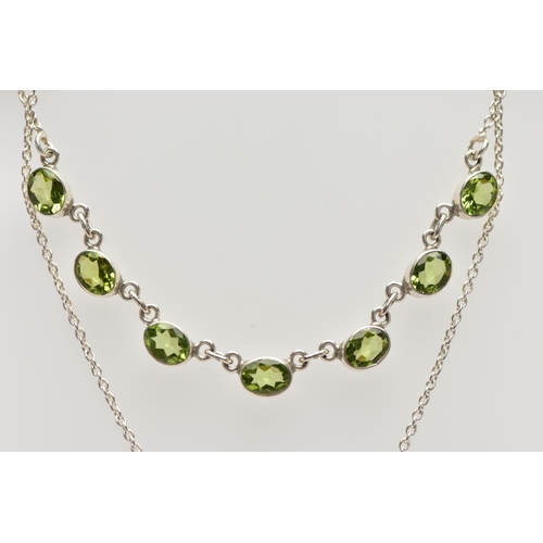 33 - A WHITE  METAL PERIDOT PENDANT NECKLACE, fitted with seven oval cut peridots each collect set into w... 