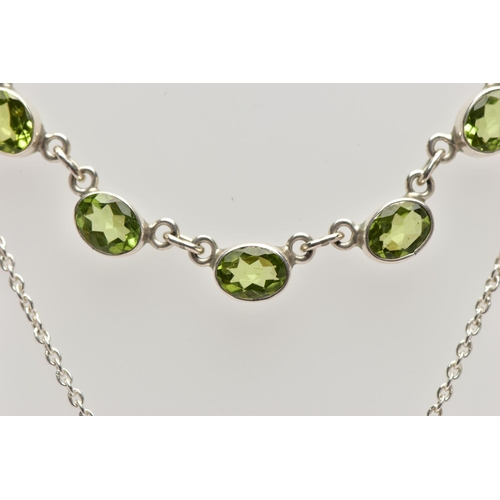 33 - A WHITE  METAL PERIDOT PENDANT NECKLACE, fitted with seven oval cut peridots each collect set into w... 