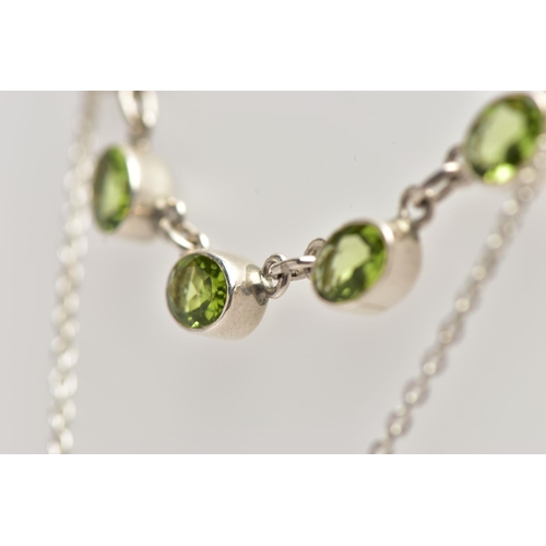 33 - A WHITE  METAL PERIDOT PENDANT NECKLACE, fitted with seven oval cut peridots each collect set into w... 