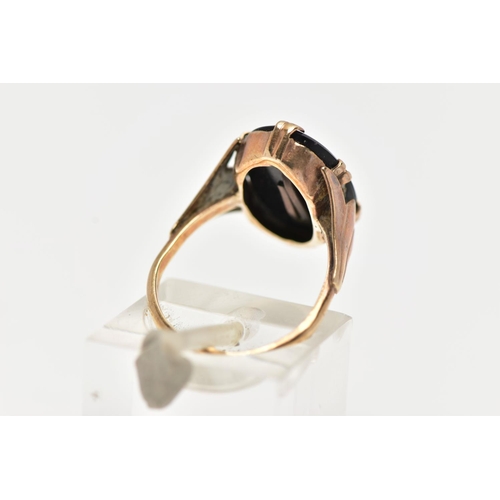 38 - A YELLOW METAL INITIAL RING, an oval cut onyx centrally set with a yellow metal letter, prong set in... 