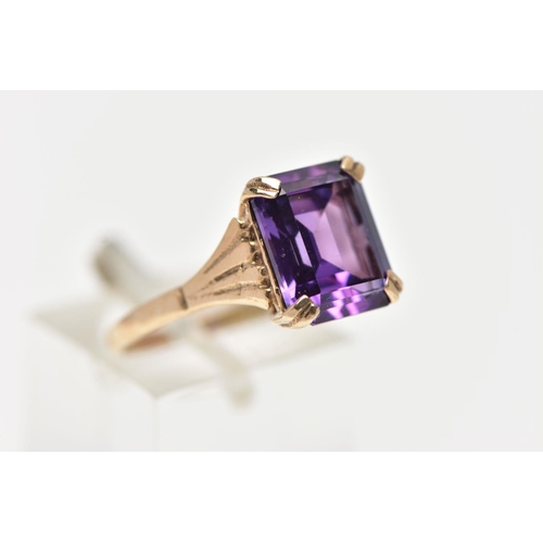 70 - A 9CT GOLD AMETHYST RING, featuring a double four claw set, rectangular cut amethyst, raised openwor... 