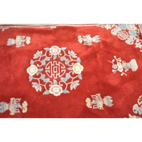 1221 - A RED GROUND WOOLEN RUG, with a multi strap border, and a central floral design 276cm x 190cm (condi... 