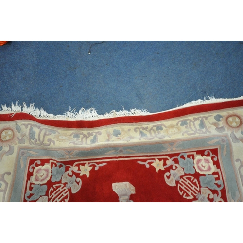 1221 - A RED GROUND WOOLEN RUG, with a multi strap border, and a central floral design 276cm x 190cm (condi... 