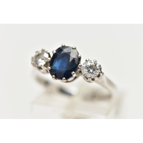 1255A - AN 18CT WHITE GOLD SAPPHIRE AND DIAMOND TRILOGY RING, centring on an oval cut deep blue sapphire, fl... 