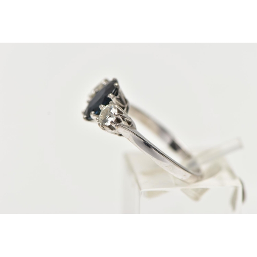 1255A - AN 18CT WHITE GOLD SAPPHIRE AND DIAMOND TRILOGY RING, centring on an oval cut deep blue sapphire, fl... 