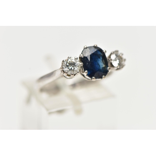 1255A - AN 18CT WHITE GOLD SAPPHIRE AND DIAMOND TRILOGY RING, centring on an oval cut deep blue sapphire, fl... 