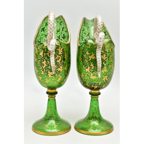 106 - A PAIR OF 19TH CENTURY BOHEMIAN GREEN AND GILT GLASS PEDESTAL EWERS OF HELMET FORM, each with a whit... 