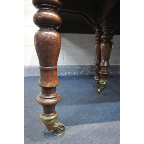 227 - A REGENCY FLAME MAHOGANY DINING TABLE, on eight turned legs with large brass caps and casters, break... 