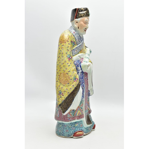 120 - A 20TH CENTURY CHINESE FAMILLE ROSE STANDING FIGURE, modelled as a male wearing flowing robes holdin... 