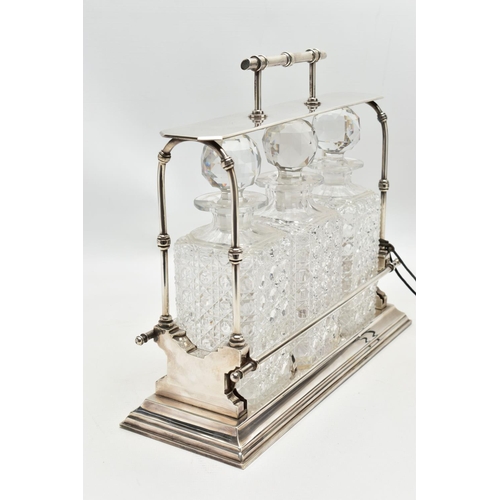 46 - A LATE VICTORIAN ELECTRO PLATED TANTALUS IN THE STYLE OF CHRISTOPHER DRESSER, the horizontal bar car... 