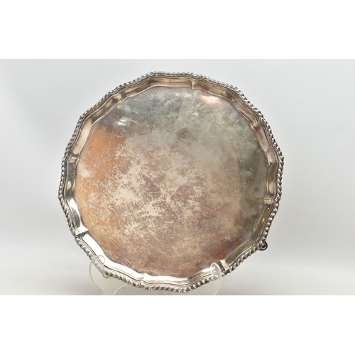 77 - A GEORGE V SILVER SALVER, with gadrooned Chippendale pie crust edge, plain centre, on four short cab... 