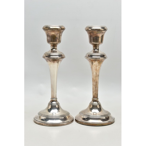 81 - A PAIR OF ELIZABETH II FILLED SILVER CANDLESTICKS, concentric reeded band decoration to the top rim,... 