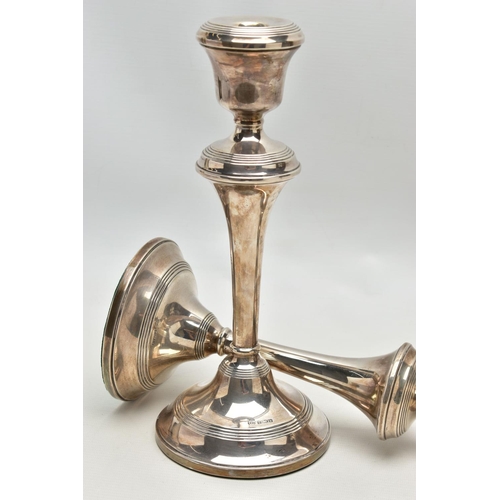 81 - A PAIR OF ELIZABETH II FILLED SILVER CANDLESTICKS, concentric reeded band decoration to the top rim,... 