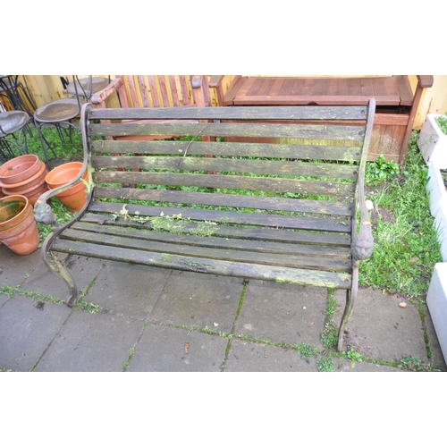 1023 - A WOODEN SLATTED GARDEN BENCH with lion mask cast iron ends 131cm wide (Condition very weathered and... 