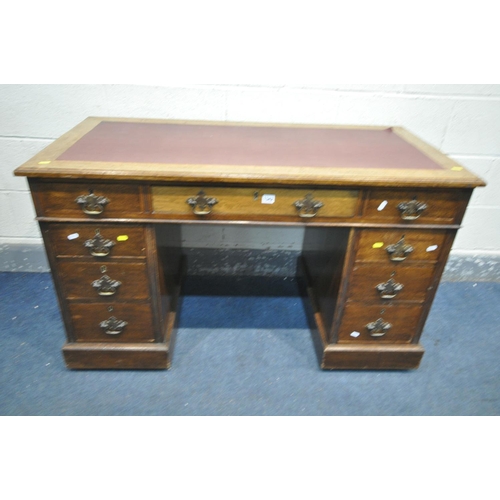 1342 - AN EDWARDIAN OAK PEDESTAL DESK, with burgundy leatherette writing surface, and nine various drawers,... 