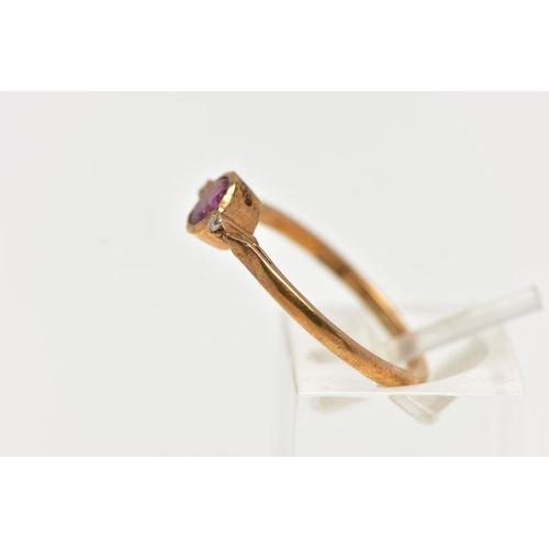 50 - A YELLOW METAL RUBY AND DIAMOND RING, designed with a collet set ruby, flanked with two small round ... 