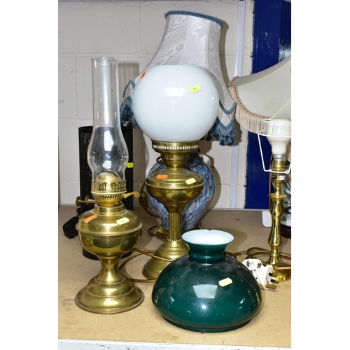 596 - EIGHT TABLE LAMPS, SHADES AND CHIMNEYS, comprising a brass based oil lamp, three electric lamps in t... 