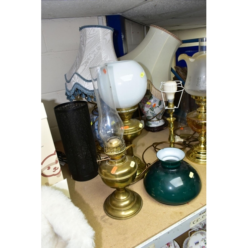 596 - EIGHT TABLE LAMPS, SHADES AND CHIMNEYS, comprising a brass based oil lamp, three electric lamps in t... 