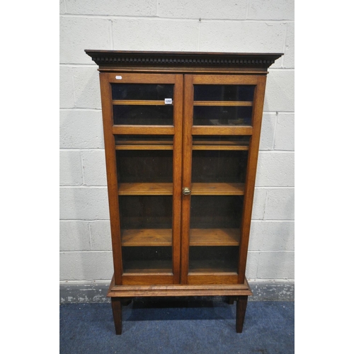 1202 - AN EARLY 20TH CENTURY OAK GLAZED TWO DOOR BOOKCASE, on square tapered legs, width 83cm x depth 31cm ... 