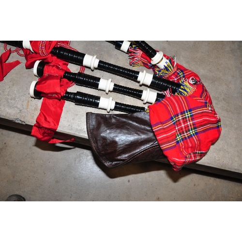 835 - A SET OF MODERN BAGPIPES with ebonised wood and plastic rings, red ribbon and tartan covering a leat... 