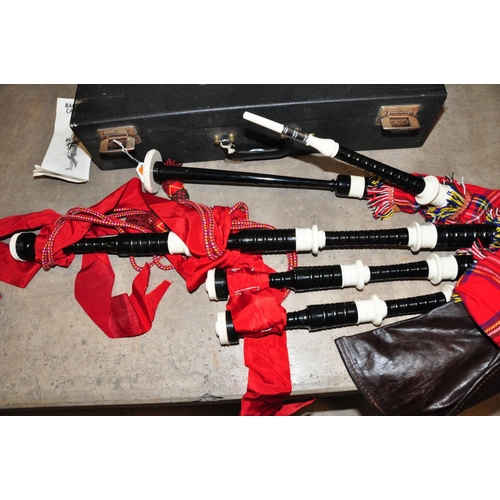 835 - A SET OF MODERN BAGPIPES with ebonised wood and plastic rings, red ribbon and tartan covering a leat... 