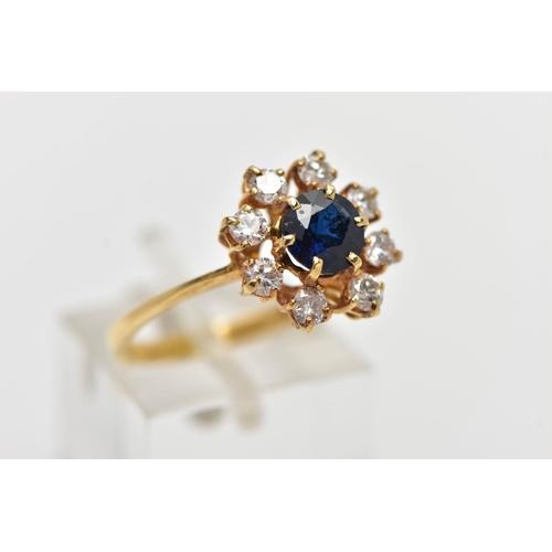 72 - AN 18CT YELLOW GOLD SAPPHIRE AND DIAMOND CLUSTER RING, centering on a circular cut blue sapphire, in... 