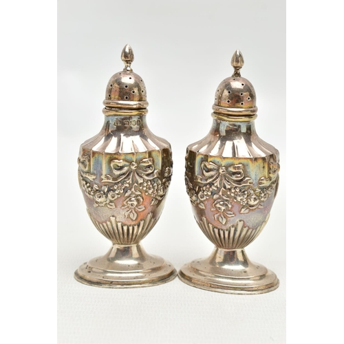 84 - A PAIR OF SILVER PEPPERETTES, decorated with an embossed floral, bow and swag design, on oval bases,... 