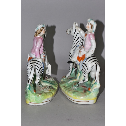 388 - A PAIR OF STAFFORDSHIRE ZEBRAS, each being ridden in a naturalistic landscape, height approximately ... 