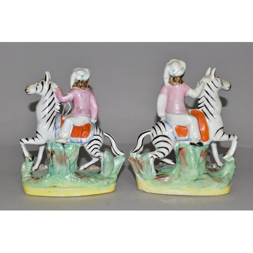 388 - A PAIR OF STAFFORDSHIRE ZEBRAS, each being ridden in a naturalistic landscape, height approximately ... 