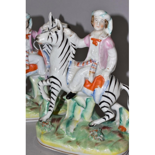 388 - A PAIR OF STAFFORDSHIRE ZEBRAS, each being ridden in a naturalistic landscape, height approximately ... 