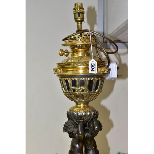 504 - A DECORATIVE ELECTRIC TABLE LAMP IN THE FORM OF AN OIL LAMP, comprising a cast brass base, reservoir... 