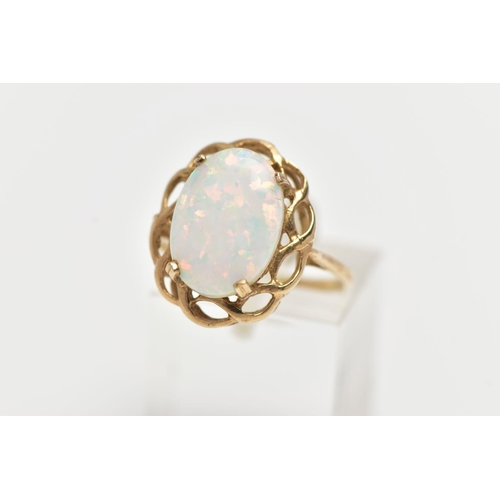 6 - A 9CT GOLD RING, designed with a four claw set, oval synthetic opal cabochon, within an openwork sca... 
