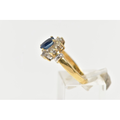 76 - AN 18CT GOLD SAPPIRE AND DIAMOND CLUSTER RING, centering on a raised oval cut blue sapphire, within ... 