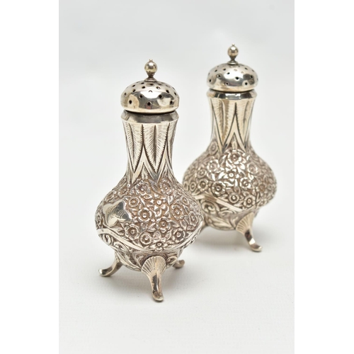 130 - A PAIR OF WHITE METAL PEPPERETTES, baluster form, decorated with a floral and foliate pattern, engra... 