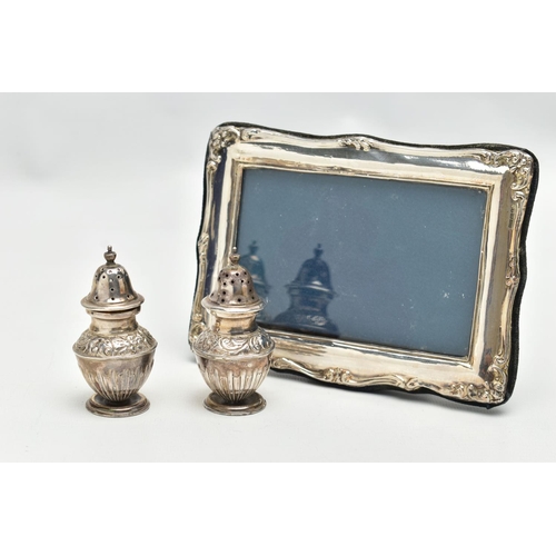 136 - A PAIR OF SILVER PEPPERETES AND A SILVER PHOTO FRAME, a pair of bluster form pepperettes, embossed w... 