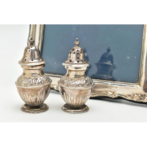 136 - A PAIR OF SILVER PEPPERETES AND A SILVER PHOTO FRAME, a pair of bluster form pepperettes, embossed w... 