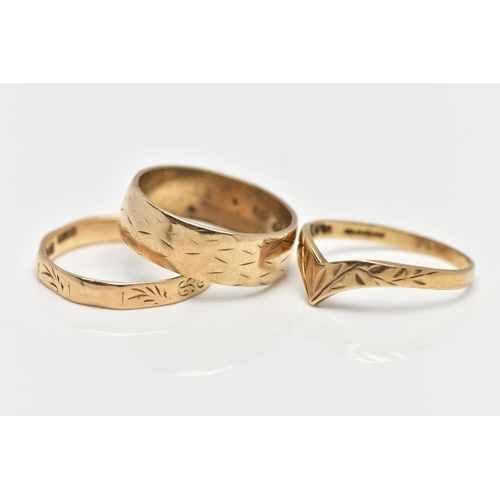 28 - THREE 9CT YELLOW GOLD RINGS, to include a wide band with engraved detail, a wish bone ring and a fac... 